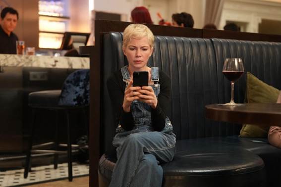A person sitting in a booth looking at her phoneDescription automatically generated