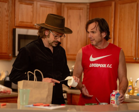 A person in a hat talking to another person in a kitchenAI-generated content may be incorrect.